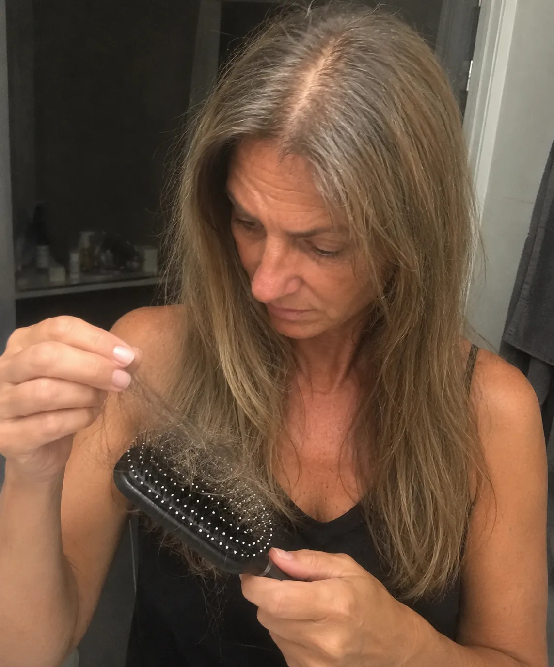 Žena gleda kosu skupljenu na četki